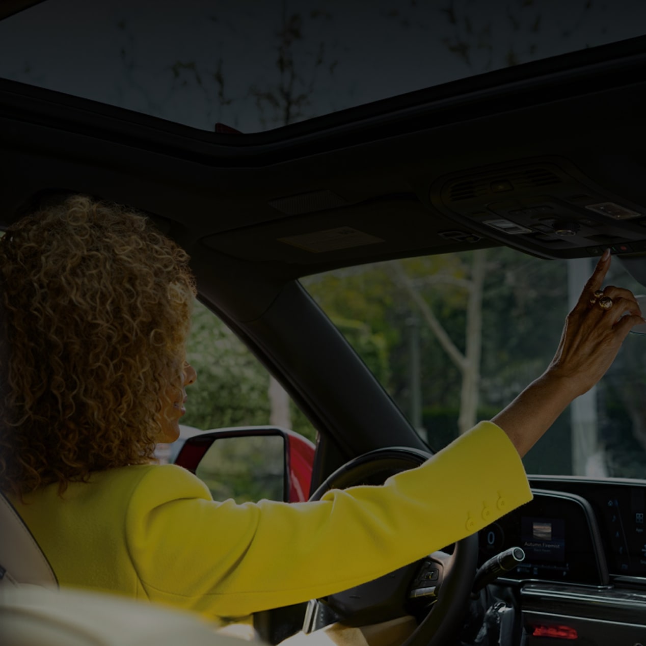 Motorista ajusta o teto solar no interior luxuoso de seu Cadillac elétrico.