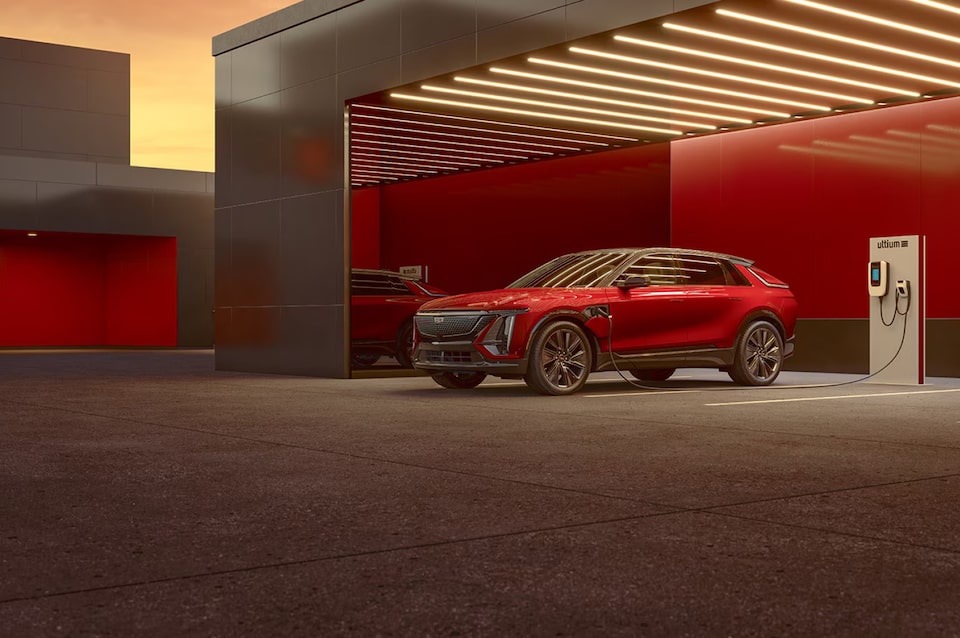 Cadillac Lyriq na cor vermelha em um ponto de recarga elétrica, destacando seu design e imponência. 