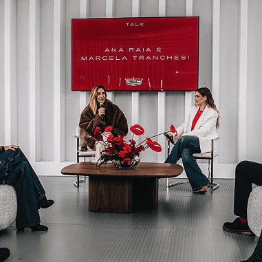 Duas mulheres estão sentadas dando uma palestra. As personalidades são: Ana Raia e Marcela Tranchesi.