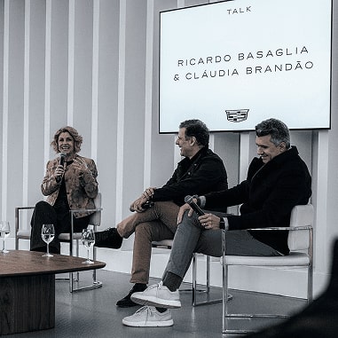 Três pessoas estão sentadas enquanto dão suas palestras. Duas delas são Ricardo Basaglia e Cláudia Brandão.