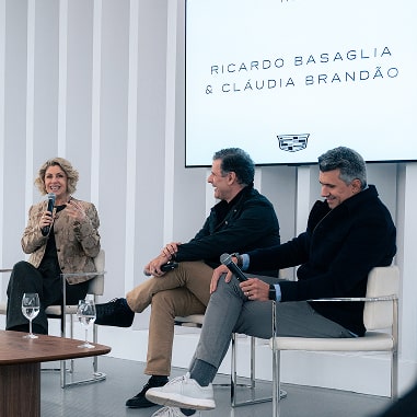 Três pessoas estão sentadas enquanto dão suas palestras. Duas delas são Ricardo Basaglia e Cláudia Brandão.