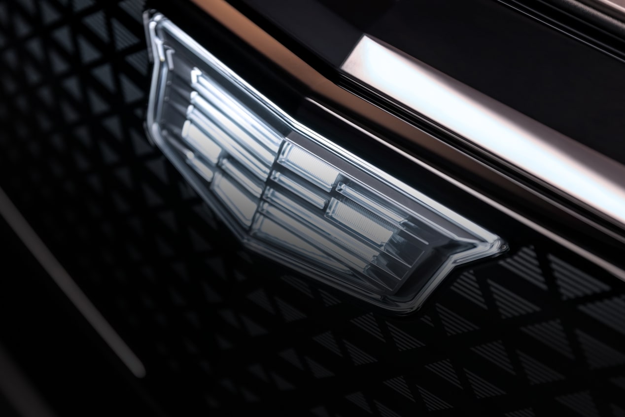 Emblema Cadillac aplicado na grade frontal do veículo em primeiro plano.