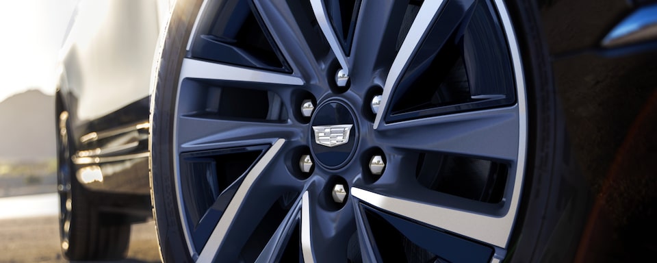 Detalhe da roda dianteira direita de um Cadillac 100% elétrico, onde o logo da marca aparece em primeiríssimo plano.