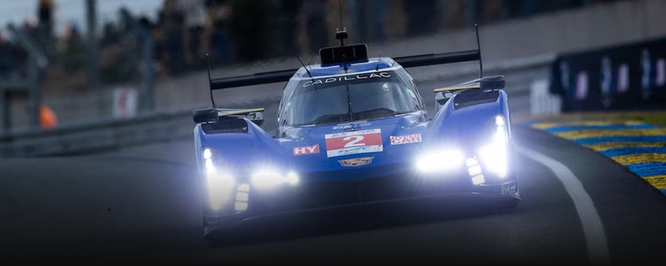 Cadillac DPI-V.R em alta velocidade fazendo a curva numa pista de corrida com faróis ligados. 