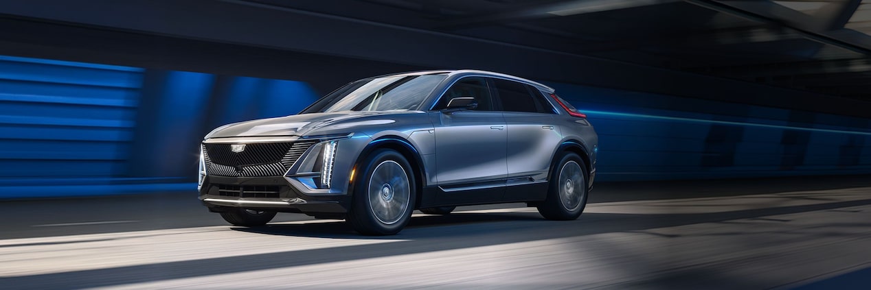 SUV elétrico Cadillac LYRIQ na cor prata em movimento, exibido em visão frontal lateral, destacando o design moderno, a iluminação em LED e as rodas de liga leve.