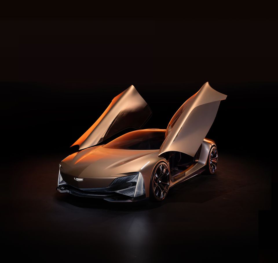 Veículo-conceito da Cadillac em acabamento metálico, exibido com as portas abertas em um ambiente escuro, destacando o design futurista, as linhas aerodinâmicas e as rodas esportivas.