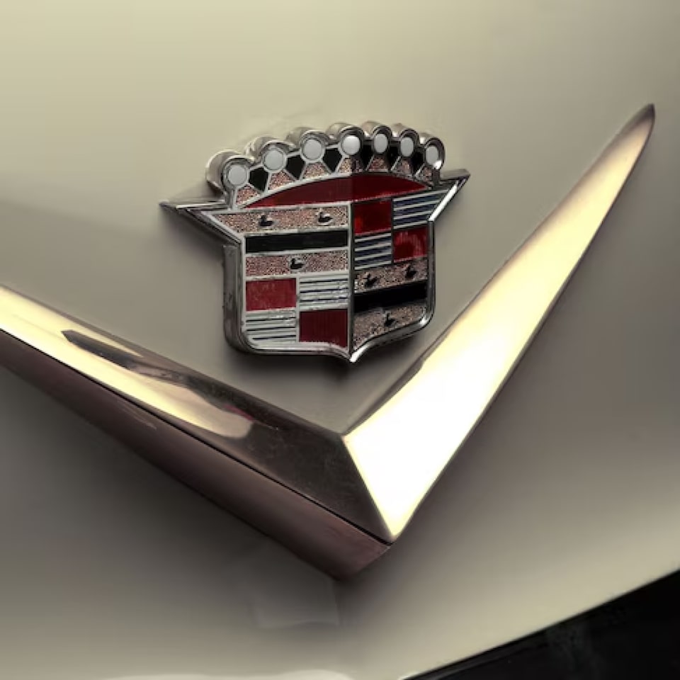 Emblema icônico da Cadillac de 1957 posicionado no capô de um veículo clássico.