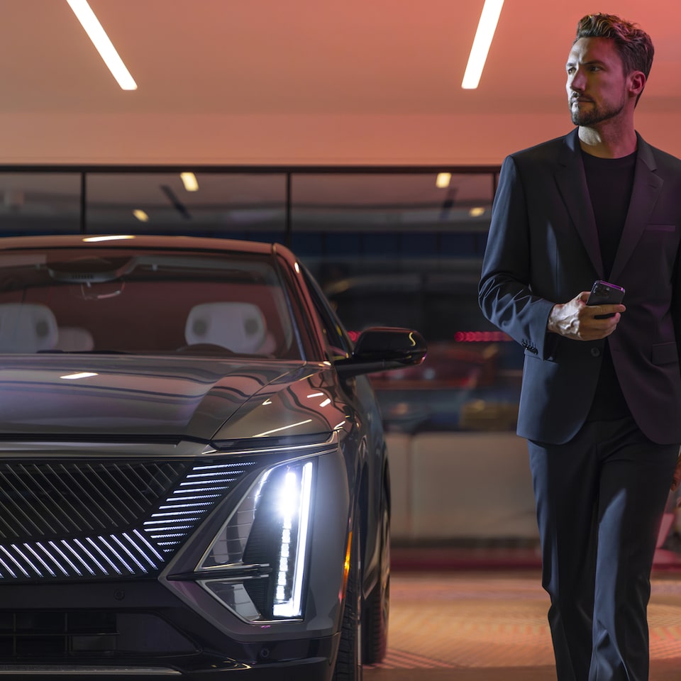 Imagem atual de um homem de terno caminhando ao lado de um Cadillac moderno, transmitindo elegância e sofisticação em um ambiente urbano. 