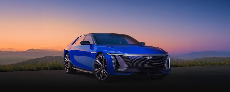 Cadillac Celestiq em imagem ambientada. O veículo, de cor azul, aparece estacionado ao ar livre, sob o sol poente e um entardecer maravilhoso.