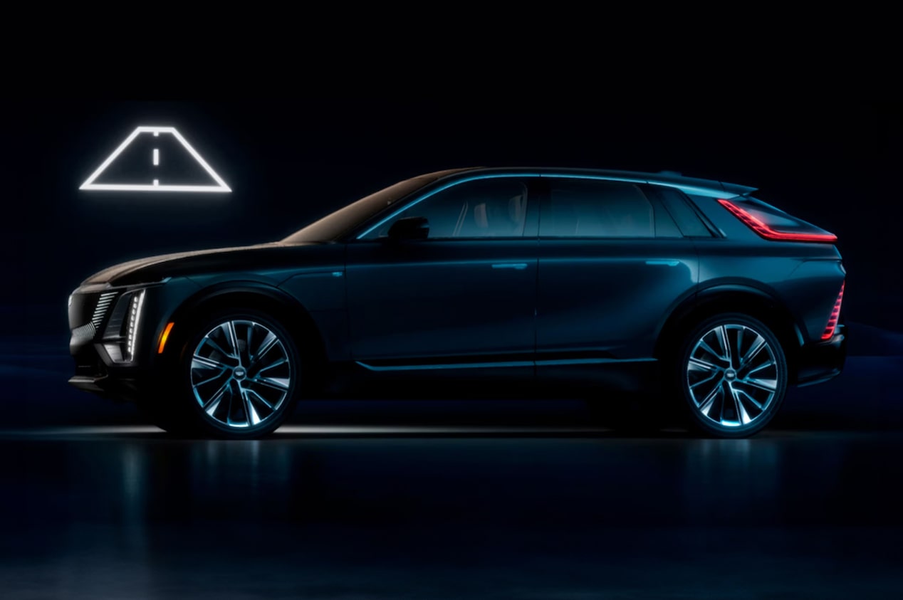 Surpreendente Cadillac Lyriq posicionado de forma lateral, com luzes baixas e um neon com símbolo de estrada logo acima.  