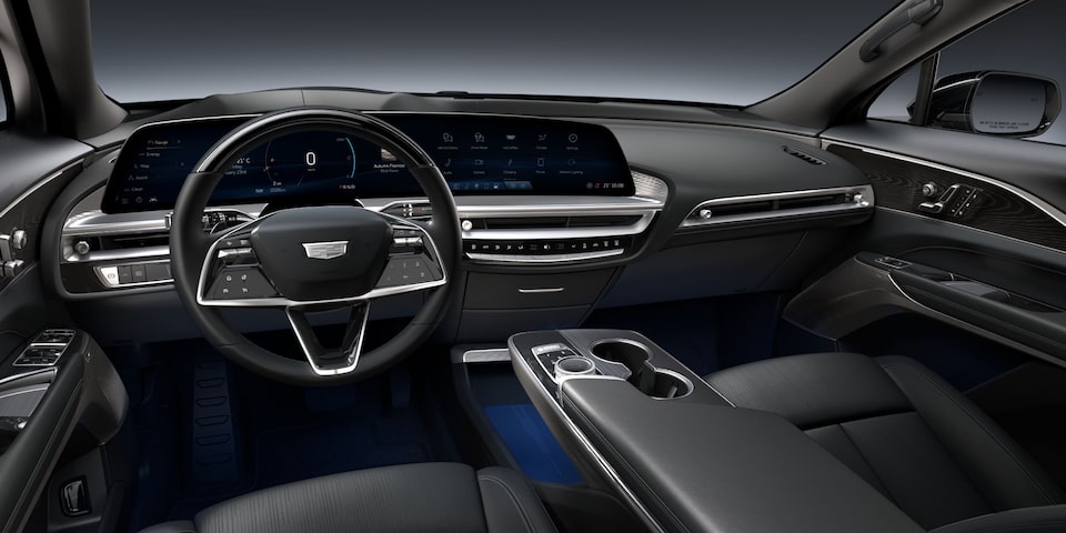 Interior do Cadillac LYRIQ com painel digital integrado, volante multifuncional, console central e acabamento premium.