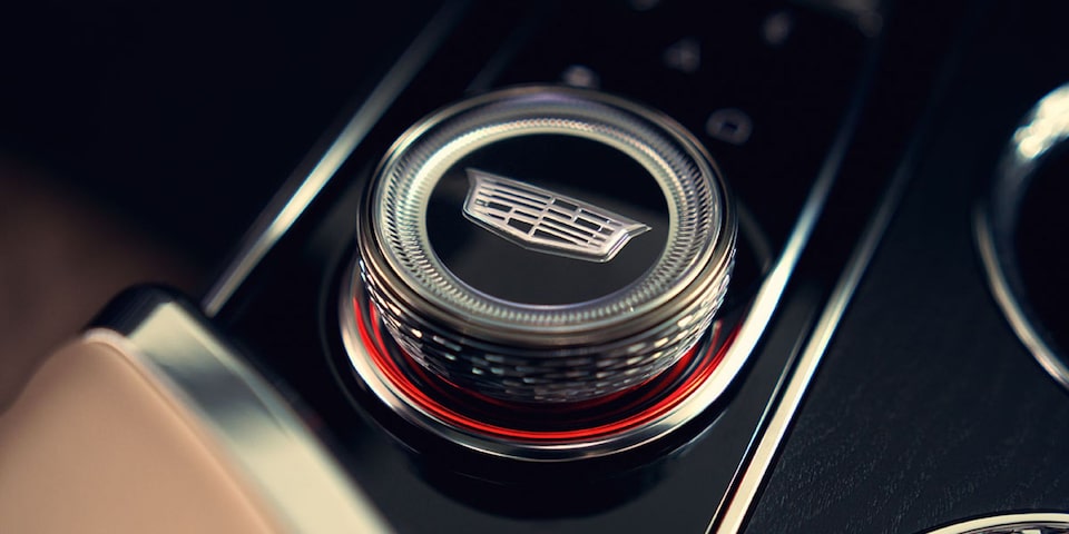Detalhe do controle giratório do console central do Cadillac LYRIQ com o emblema da Cadillac.
