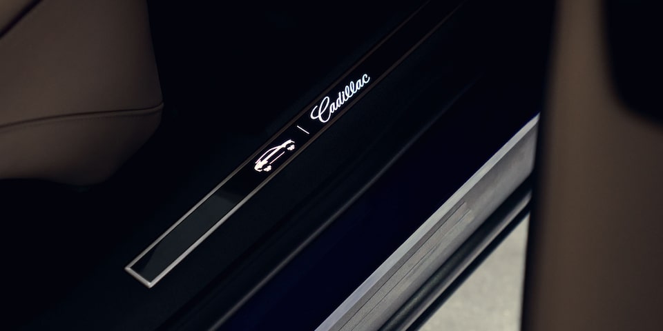 Soleira iluminada do Cadillac Lyriq com assinatura da marca: acabamento premium e atenção aos detalhes no interior do veículo.