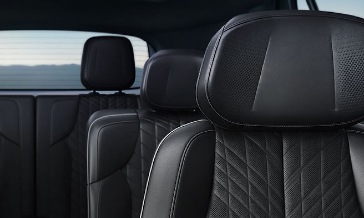 Interior de veículo Cadillac com bancos revestidos em couro preto, encostos de cabeça integrados, costuras em padrão losango e acabamento premium em tons escuros.