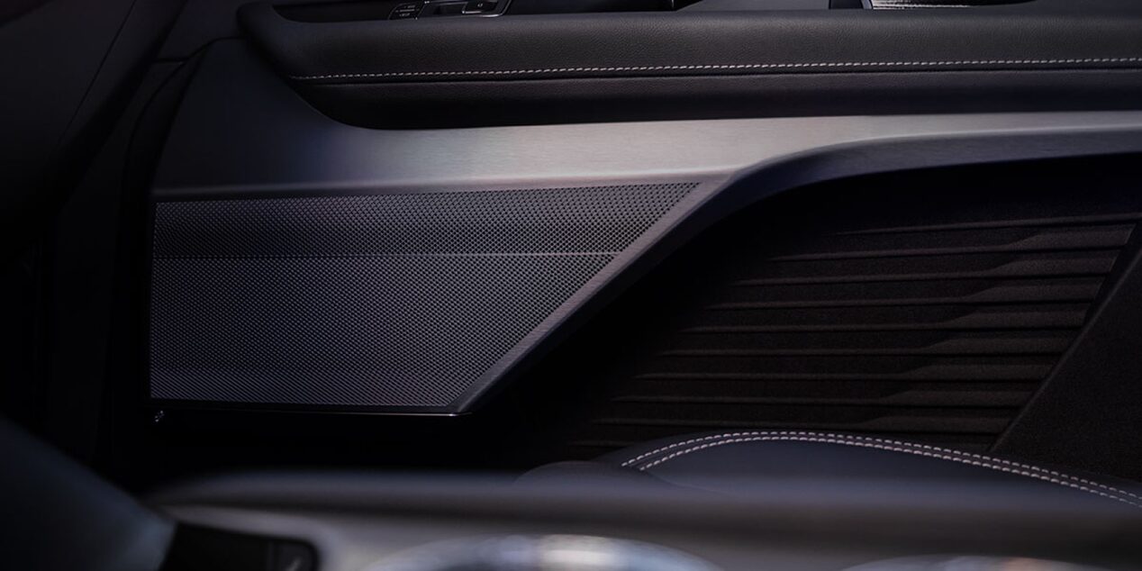 Detalhe do acabamento interno da porta de um veículo Cadillac, com revestimento premium, linhas sofisticadas e acabamento em tons escuros.