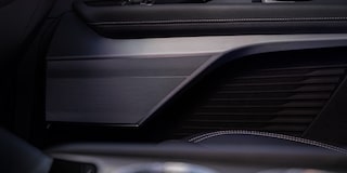 Interior de veículo Cadillac com painel digital integrado, volante multifuncional, central multimídia, console central e acabamento premium em tons escuros, com vista para uma paisagem montanhosa ao fundo.