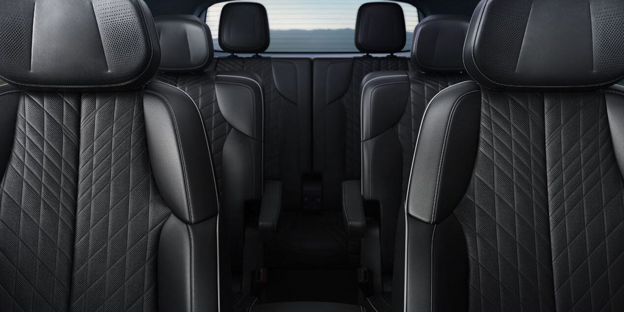 Interior de veículo Cadillac com bancos revestidos em couro preto, acabamento premium, costuras em padrão losango e cabine espaçosa.
