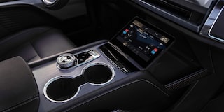 Interior de veículo Cadillac com bancos revestidos em couro preto, acabamento premium, costuras em padrão losango e cabine espaçosa.