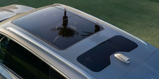 Detalhe da dianteira de um veículo Cadillac na cor azul, destacando a grade frontal, a iluminação em LED e o acabamento sofisticado.