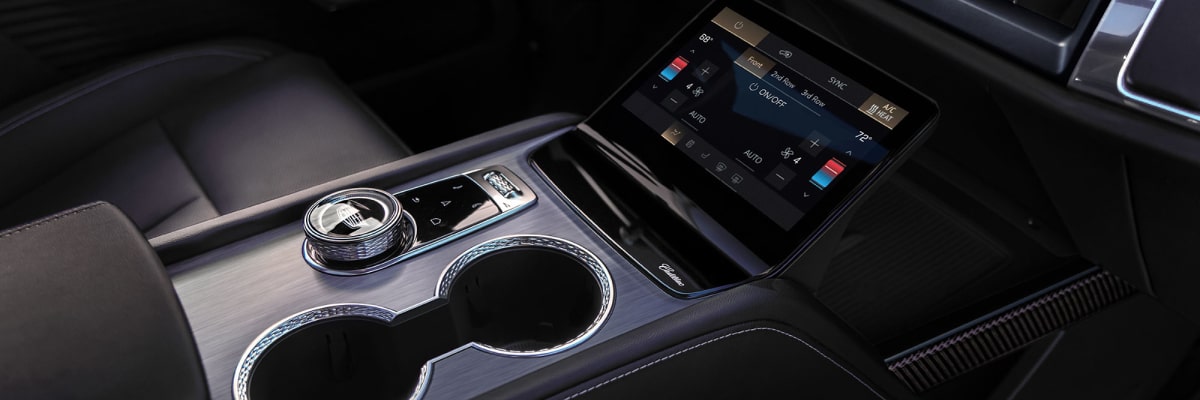 Console central do Cadillac LYRIQ com porta-copos duplo, seletor de marcha rotativo e acabamento premium, destacando o design sofisticado e a tecnologia do interior do veículo.
